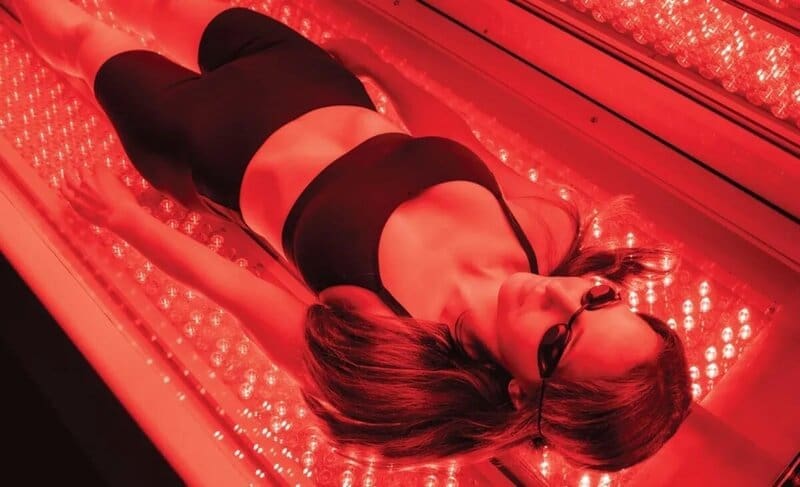 Woman in red light therapy bed at The Wellness Spot Vero Beach